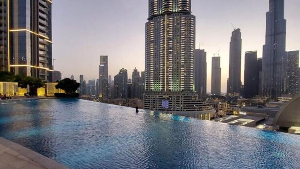Una piscina con vista a un paisaje urbano, que incluye rascacielos y una torre distintiva.