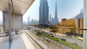 Un balcón con sillas de mimbre y vistas a un paisaje urbano que incluye el Burj Khalifa.