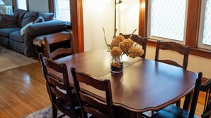 A dining area with a wooden table and chairs, a vase with dried flowers, and a lamp. - My Sisters Place | Sleeps 6 • Piano & Pool Table (Concord)