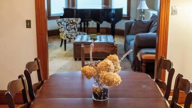 A dining room with a wooden table and chairs, a chandelier, and a vase with dried flowers. - My Sisters Place | Sleeps 6 • Piano & Pool Table (Concord)
