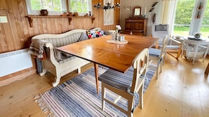 Een knus vertrek met een houten eettafel, een beklede bank en een kroonluchter.