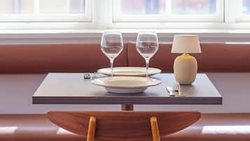 A dining area with a table set for two, a lamp, and a chair.