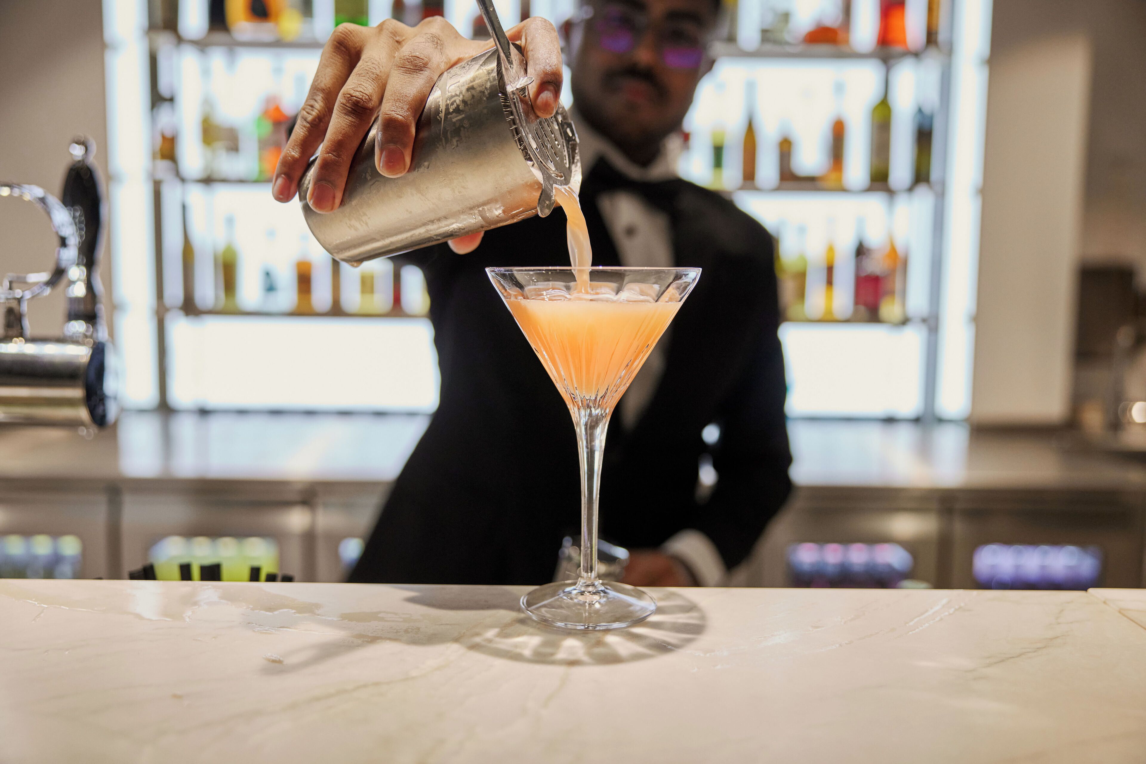 Un barman verse une boisson dans un verre à martini.