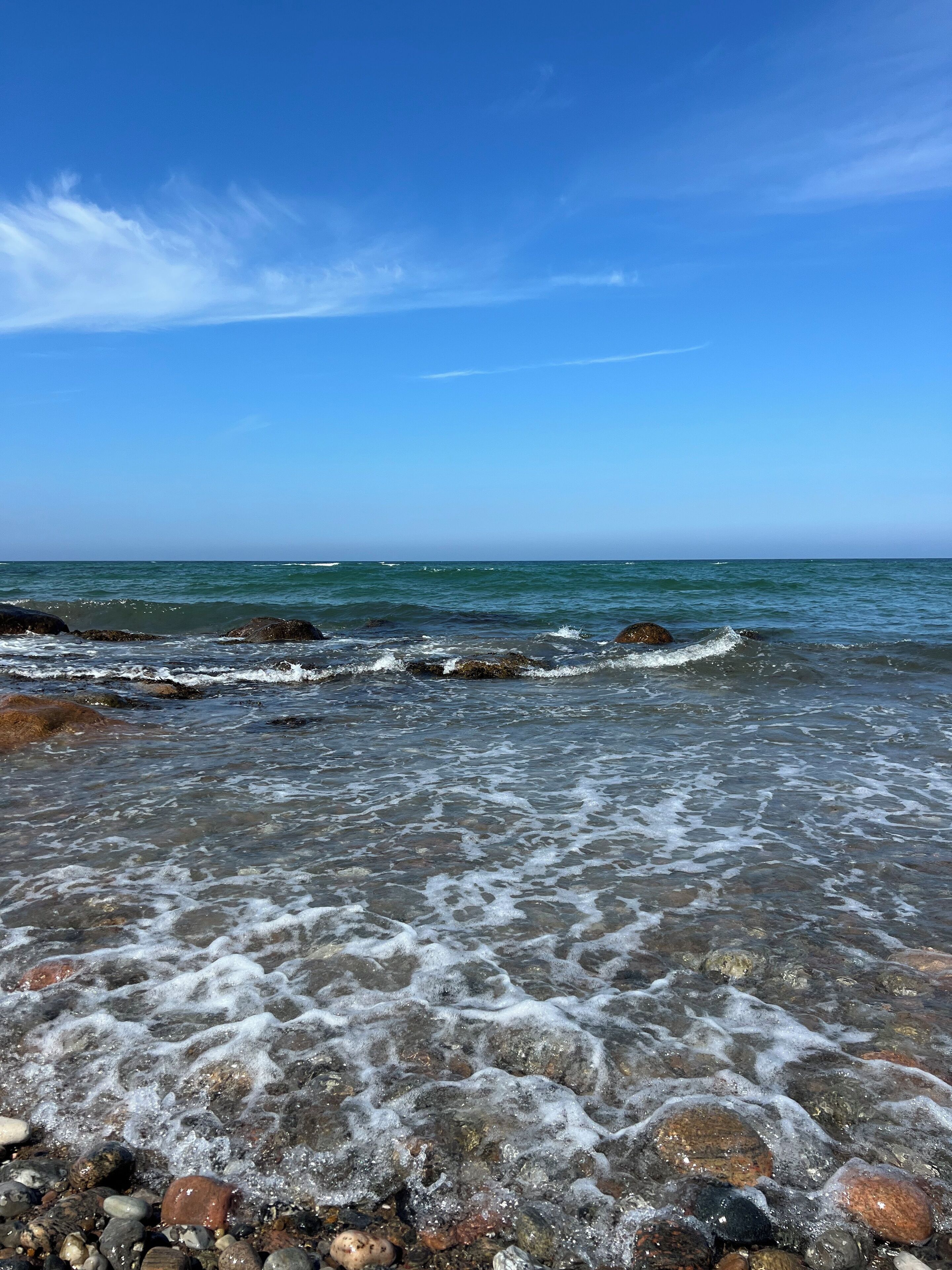 A rocky beach with clear water and waves.