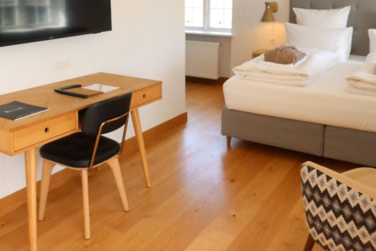 Ein Hotelzimmer mit Bett, Schreibtisch mit Stuhl, Fernseher und Lampe.