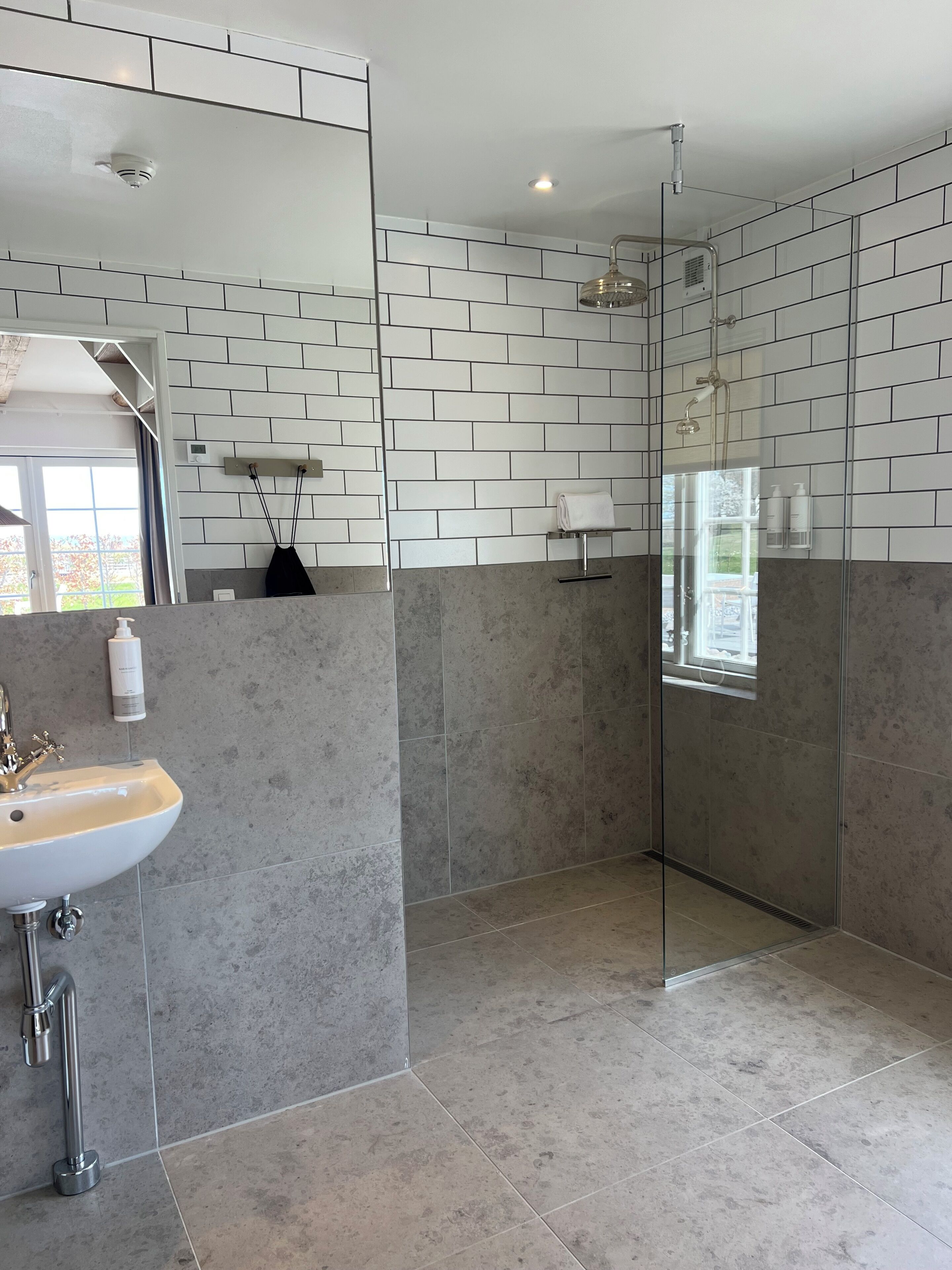 Un baño moderno con cabina de ducha de vidrio, un lavamanos con encimera de mármol y una pared de azulejos con diseño de ladrillo.