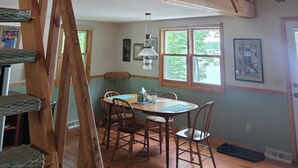 A dining area with wooden furniture, a staircase, and a loft space with exposed beams. - Waterfront cabin on Long Lake. (New Auburn)