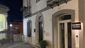 Ein Gästehaus namens "Antico Mulino" mit einer Steinfassade, Rundbögen und einem kleinen Balkon mit schmiedeeisernen Geländern.