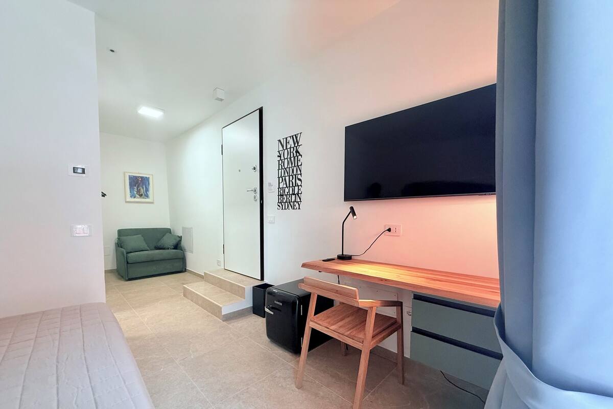 Een moderne kamer met een bureau, stoel en een wandgemonteerde flatscreen-tv.