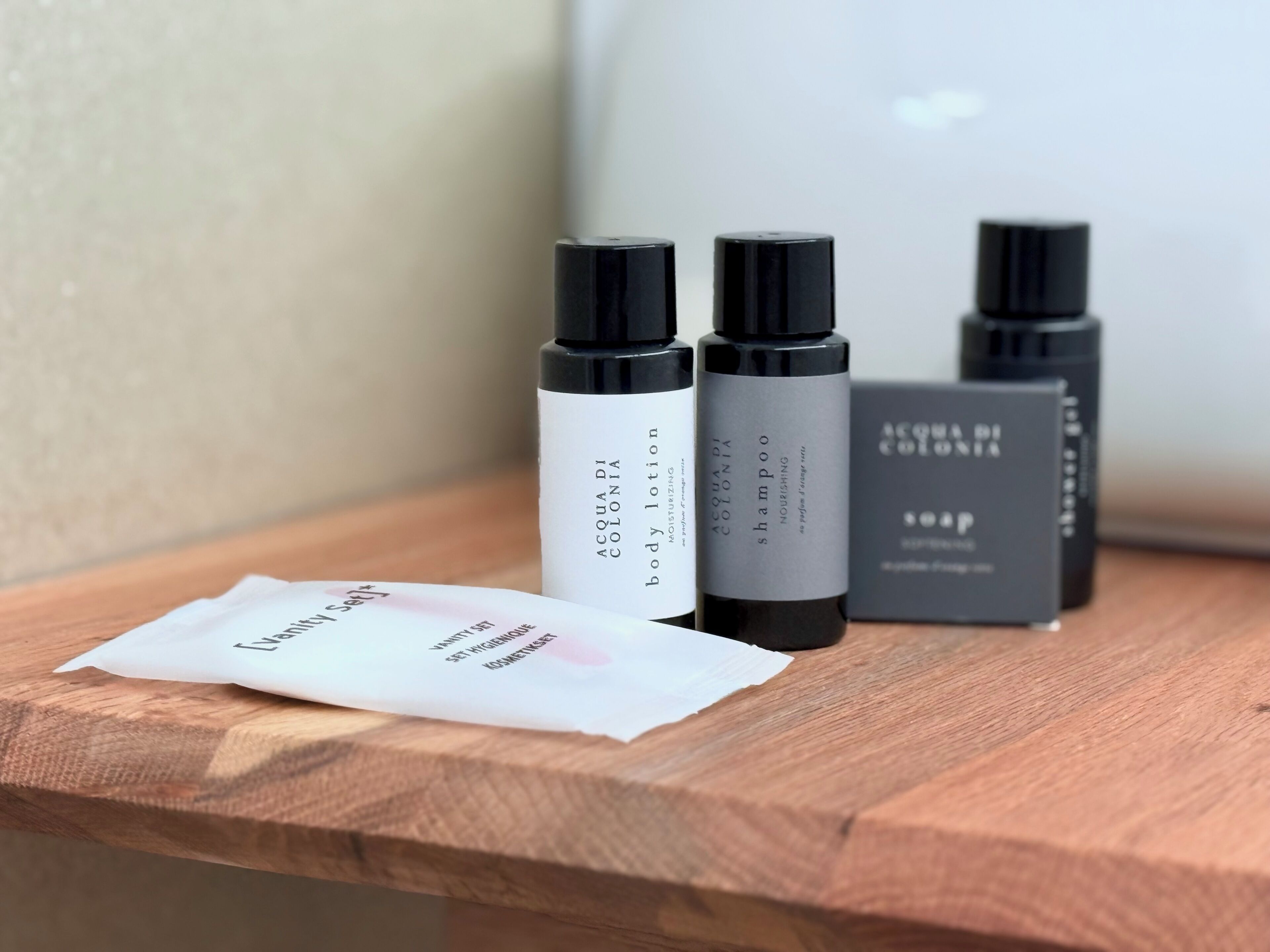 Three bottles of body lotion and shampoo on a wooden surface.