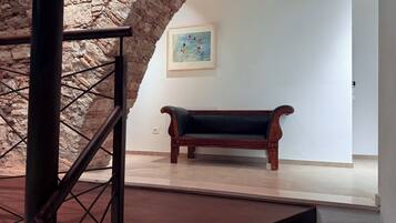 A staircase with a stone wall, a wooden bench, and a framed painting on the wall.