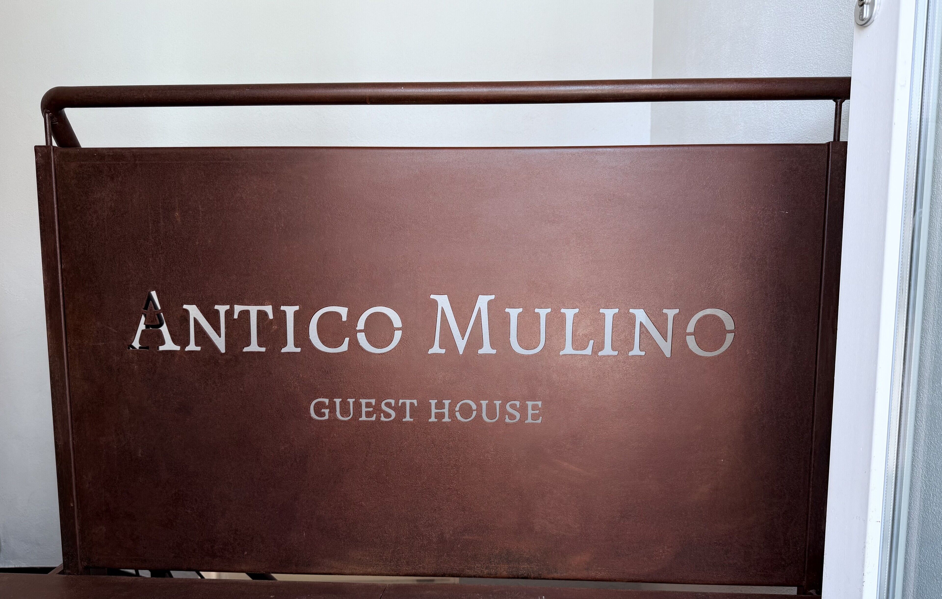 Una señal marrón con el texto 'ANTICO MULINO GUEST HOUSE'.