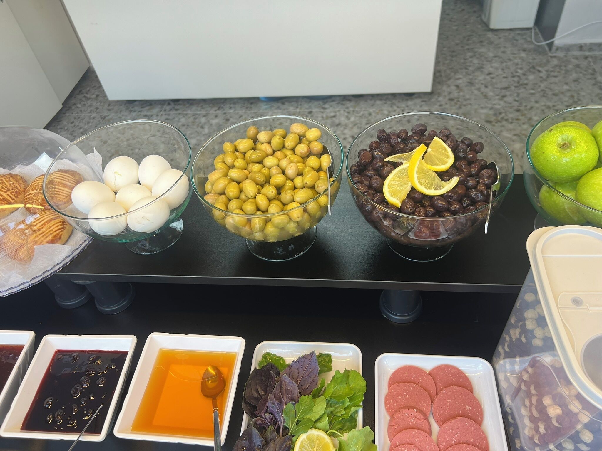 Ett buffébord med olika sorters mat, inklusive ägg, oliver, chokladdoppade dadlar och olika såser.