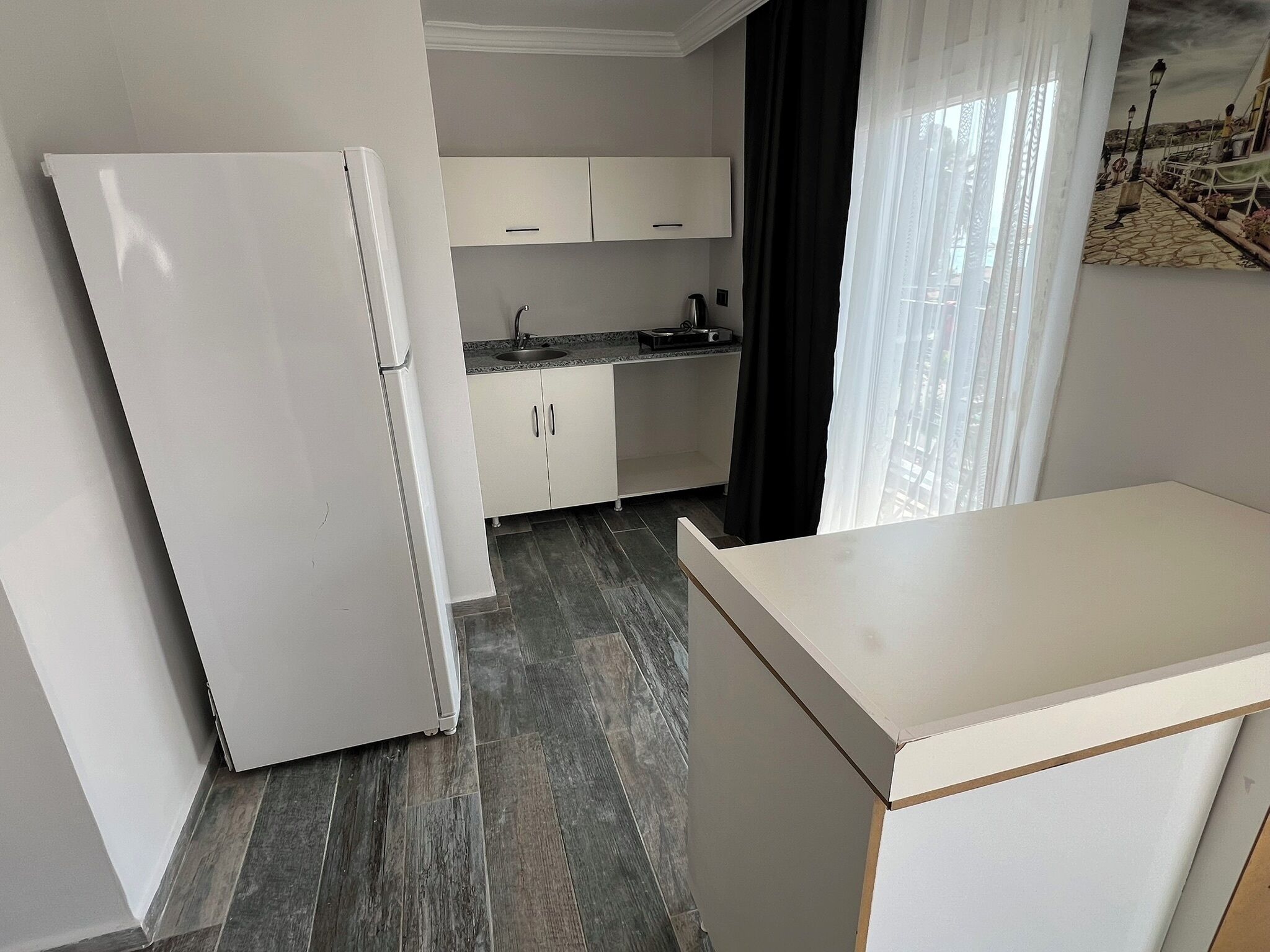 A compact kitchen with white cabinets, a built-in sink, and a refrigerator.