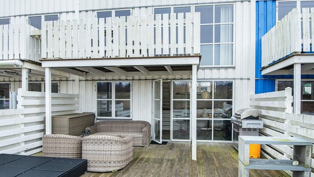 Un espace extérieur abrité, doté d'une terrasse en bois, de meubles en osier et d'un barbecue.