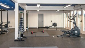 Une salle de sport équipée de matériel de musculation, de machines de cardio et dont le plafond est décoré d’un motif bleu.