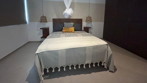 Une chambre à coucher avec un grand lit, deux tables de chevet, une tête de lit et une armoire.