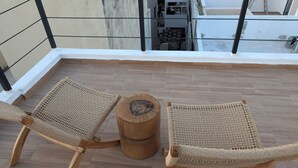 Un balcon avec deux fauteuils en osier et une table en bois.