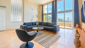 A modern living room with a grey sofa, a round coffee table, and a patterned rug.