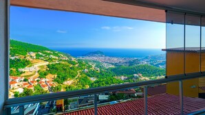 A balcony with a view of a coastal town and the sea.