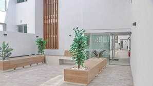 A modern indoor space with built-in planters, a glass door entrance, and a wooden slatted wall. - Apartamento Terrazas de Conil (conil de la frontera)