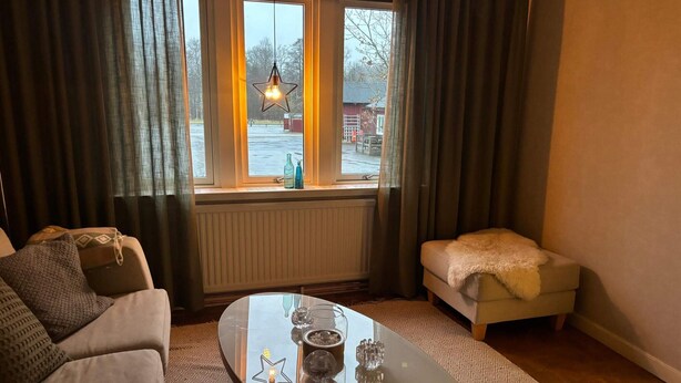 Een gezellige woonkamer met een bank, een kleine tafel en een raam met gordijnen.