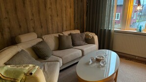 Een woonkamer met een bank, een salontafel en een raam met gordijnen.