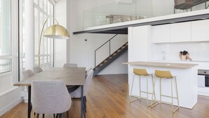 A modern kitchen with a wooden island, bar stools, and a staircase leading to an upper level.