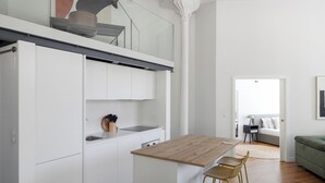 A modern kitchen with white cabinets, a wooden countertop, and a bar stool.