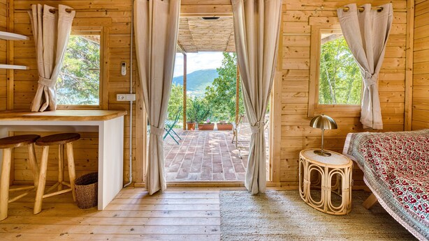 Una cabaña de madera con una cama, un escritorio y vistas al exterior.
