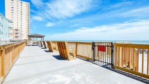 A wooden boardwalk leading to a beach with a high-rise building in the background.