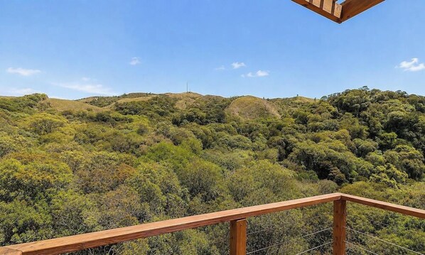 A view from a wooden balcony overlooking a hilly landscape with dense vegetation. - Cabana de Luxo na Serra Catarinense Vst018 (Anitapolis)