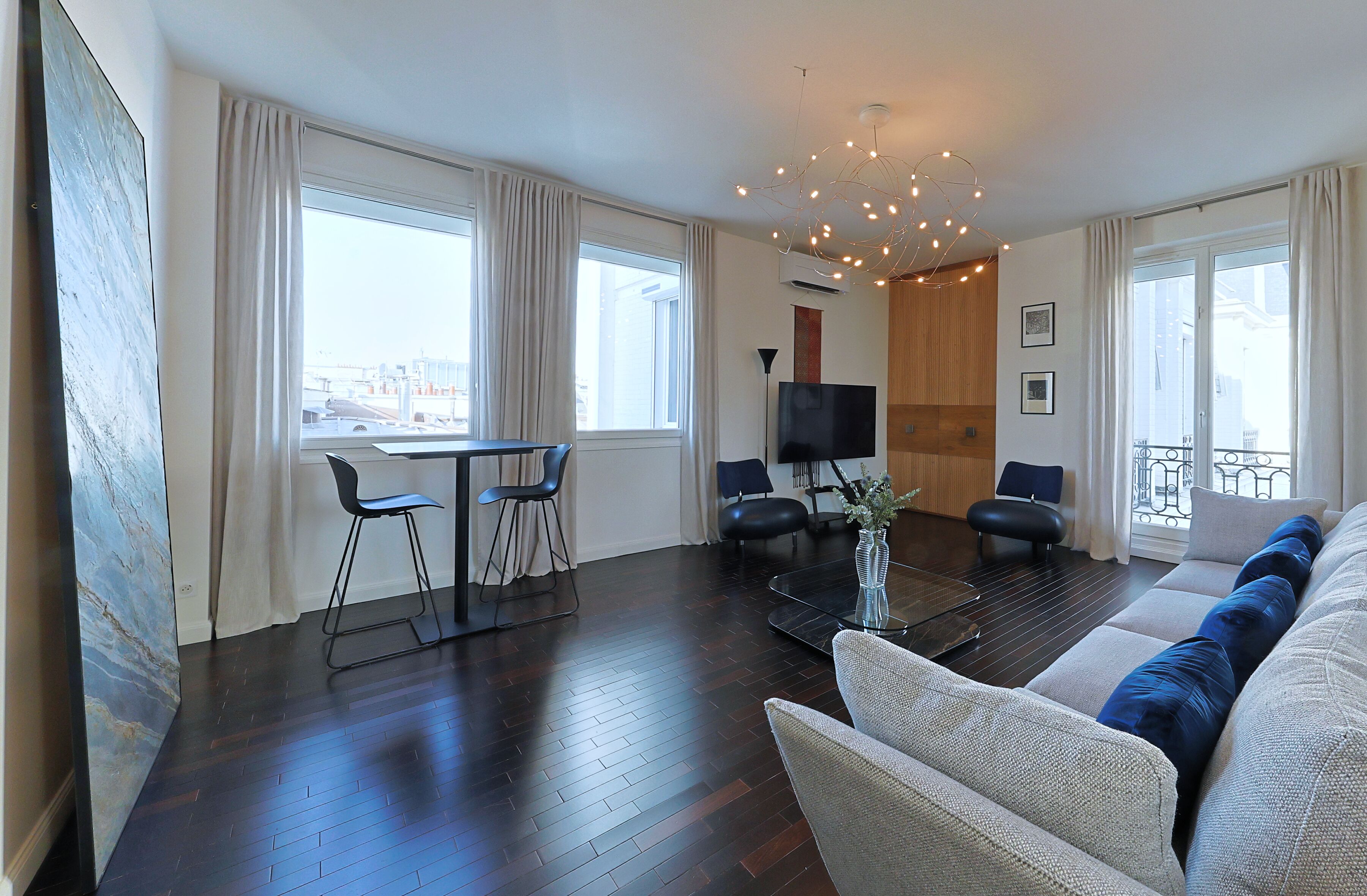 Een moderne woonkamer met een bank, twee stoelen, een salontafel en een televisie.
