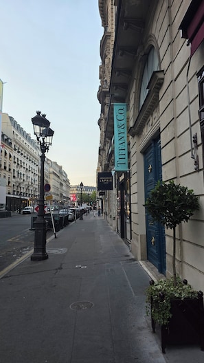 Una calle con un edificio que muestra un cartel de 'TIFFANY & CO'.