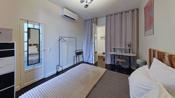 A hotel room with a bed, a desk, a mirror, and a bathroom visible through an open door.