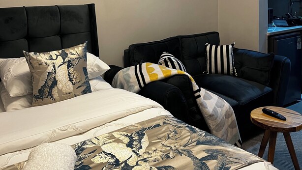 A hotel room with a bed, two sofas, a small table, and a desk with a computer. - Step into effortless luxury at The Mesquite Studio. (Nairobi)