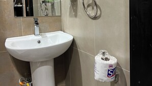 A bathroom with a white sink, a mirror, a towel rack, and a toilet paper dispenser. - Step into effortless luxury at The Mesquite Studio. (Nairobi)