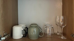 A wooden shelf with various glassware and ceramic mugs. - Step into effortless luxury at The Mesquite Studio. (Nairobi)