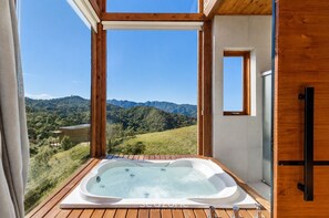 A hot tub on a wooden deck with a mountain view.