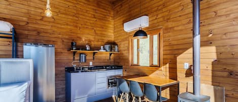 A compact kitchen with a stove, refrigerator, and a dining area with chairs.