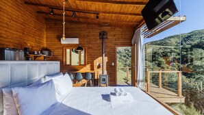 Une cabane en bois comprenant un lit, un coin repas et une cuisine.
