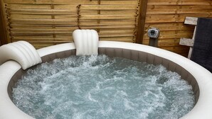 Un bain à remous avec un mur en bois en arrière-plan.