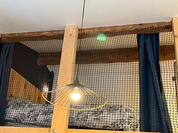 A room with a wooden ceiling, a hanging light fixture, and a netted window.