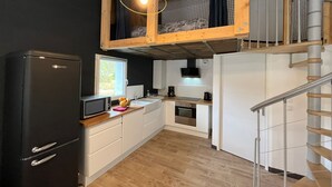 Une cuisine de taille réduite, équipée d’un réfrigérateur, d’un four à micro-ondes et de meubles de rangement en bois.