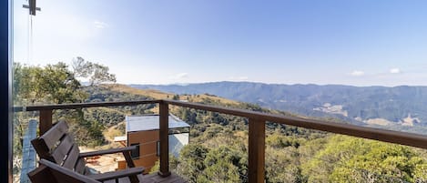 Una terraza de madera con vista a un paisaje montañoso.