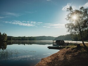 A lakeside cabin with a dock, surrounded by trees and hills. - 4 Person Holiday Park Home in Rolfstorp (Rolfstorp)