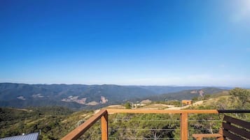 A panoramic view from a high vantage point overlooking a valley with a wooden railing and a bench.
