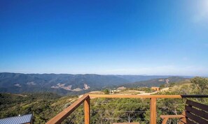 A scenic overlook with a wooden railing, a clear blue sky, and a view of distant hills.