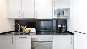 Una cocina moderna con armarios blancos, microondas integrado, cafetera y tostadora.