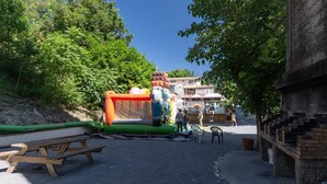 Ett utomhusområde med en stor uppblåsbar konstruktion, picknickbord och en mur av tegelsten.